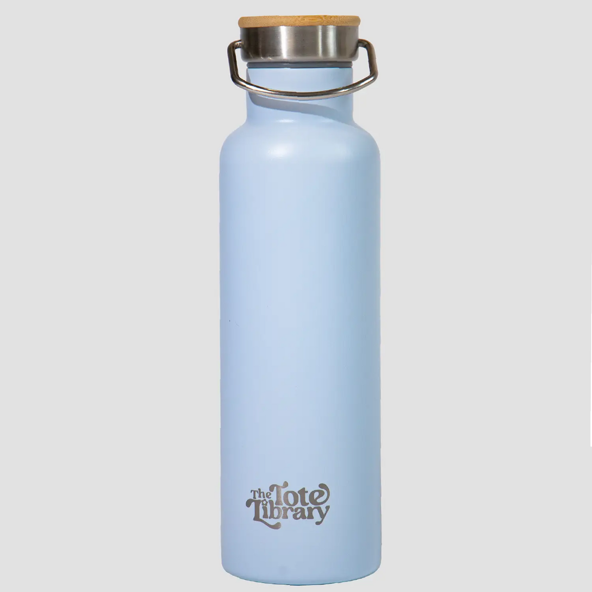 A light blue stainless steel water bottle with a bamboo-topped lid, displayed next to its packaging which has floral designs and the brand 'TTL' printed on it.