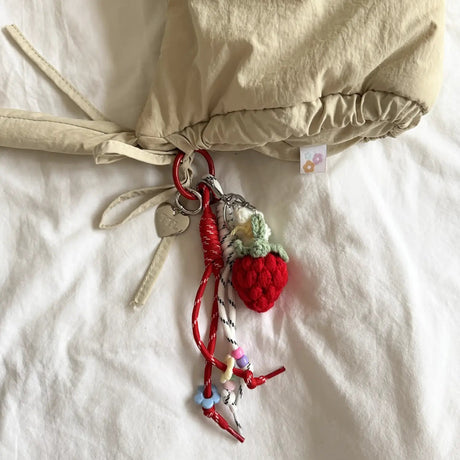 Keychain with strawberry charm attached to a beige bag on a white surface
