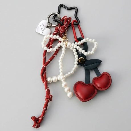 Keychain with red heart, white beads, and black accents on a gray background with a cherry