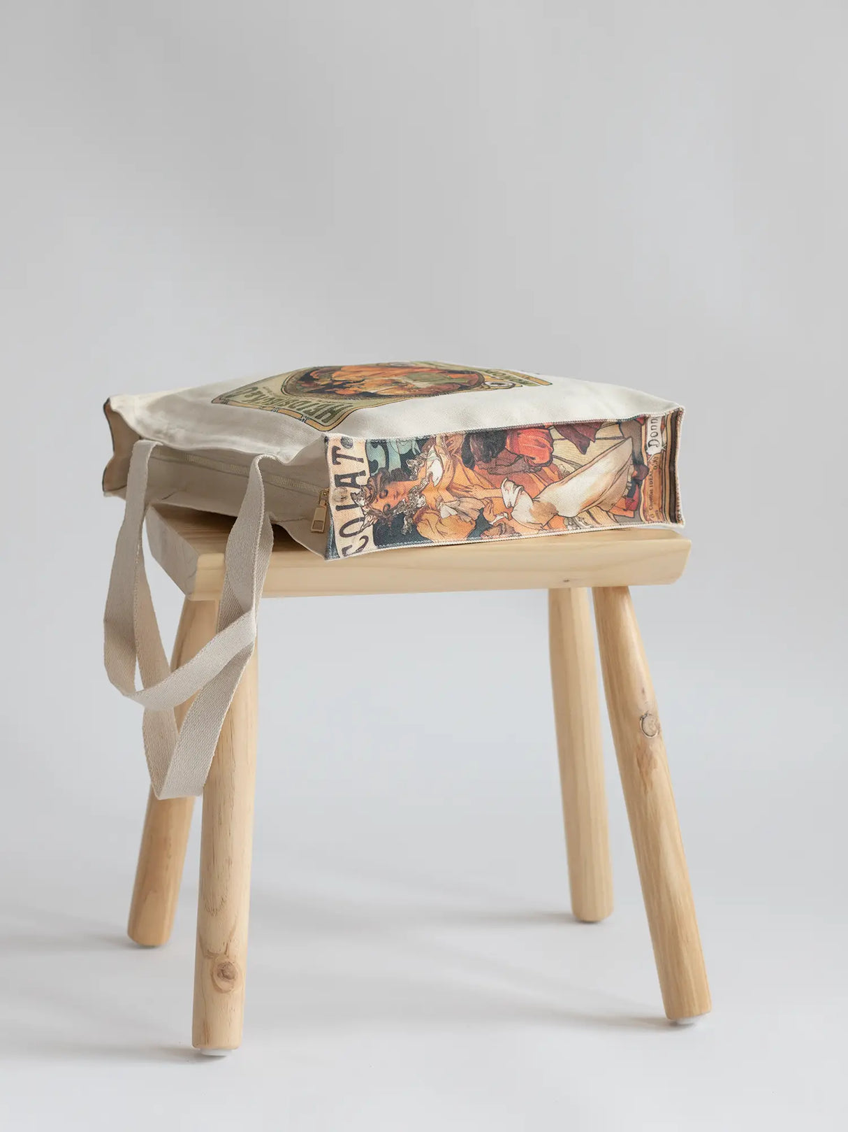 Alphonse Maria Mucha "Heidsieck Monopole" - Thick Canvas Tote Bag on a chair showcasing the art on the side