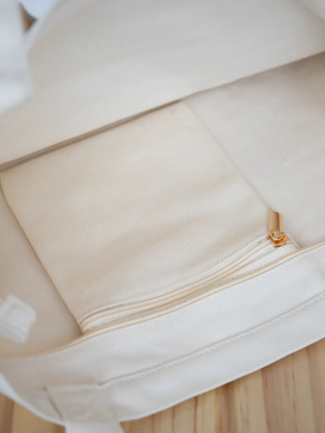 Sand Mini Functional Tote Bag on a chair  showcasing the inside metal zipper pocket from The Tote Library