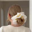 Person with a bun held by a decorative hair tie against a neutral background