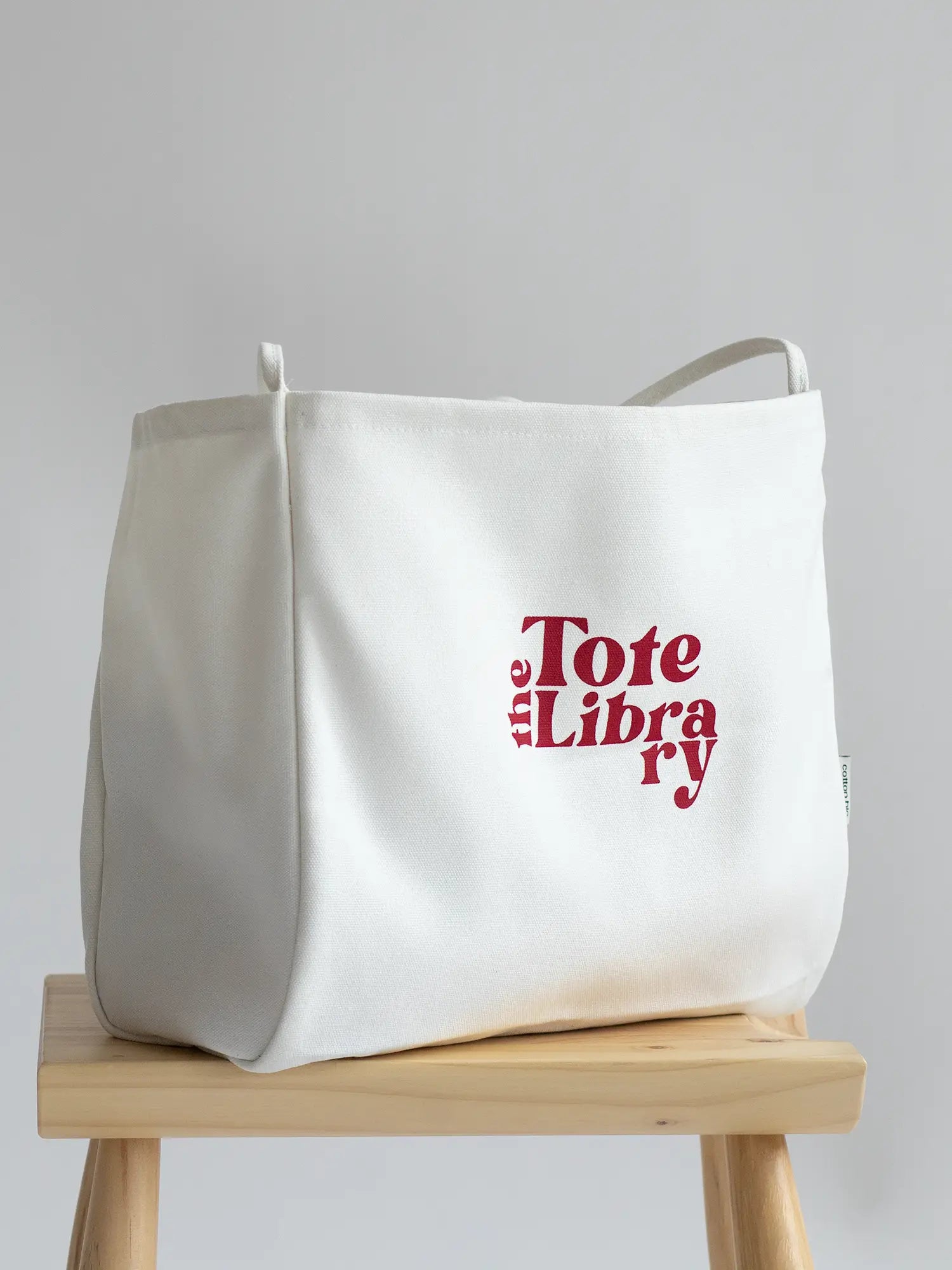 White Coastal Carryall functional tote on a chair with The Tote Library logo on it
