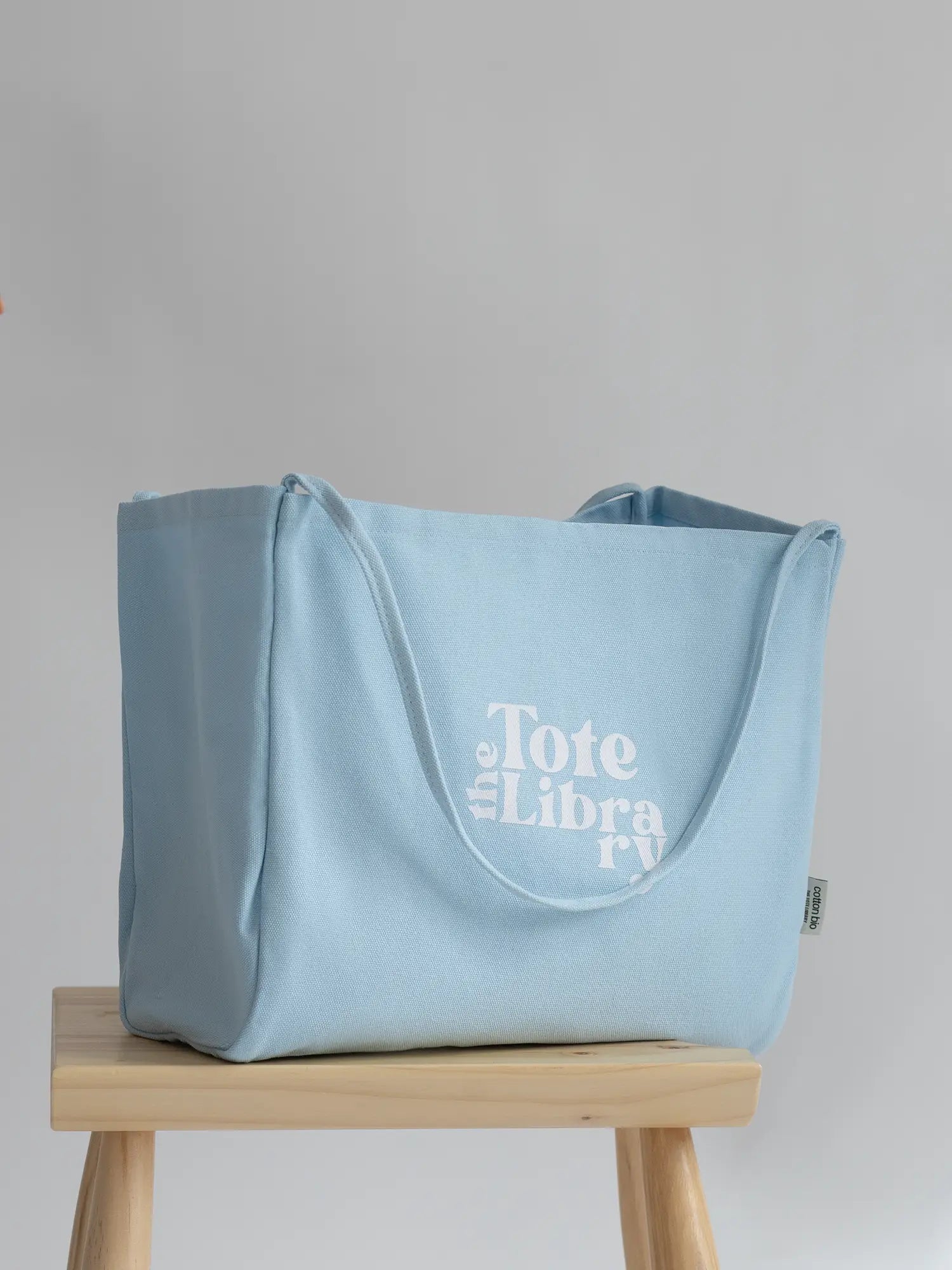 Sky Blue Coastal Carryall functional tote on a chair with The Tote Library logo on it