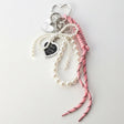Pearl bracelet with heart-shaped charms and a pink cord on a light gray background